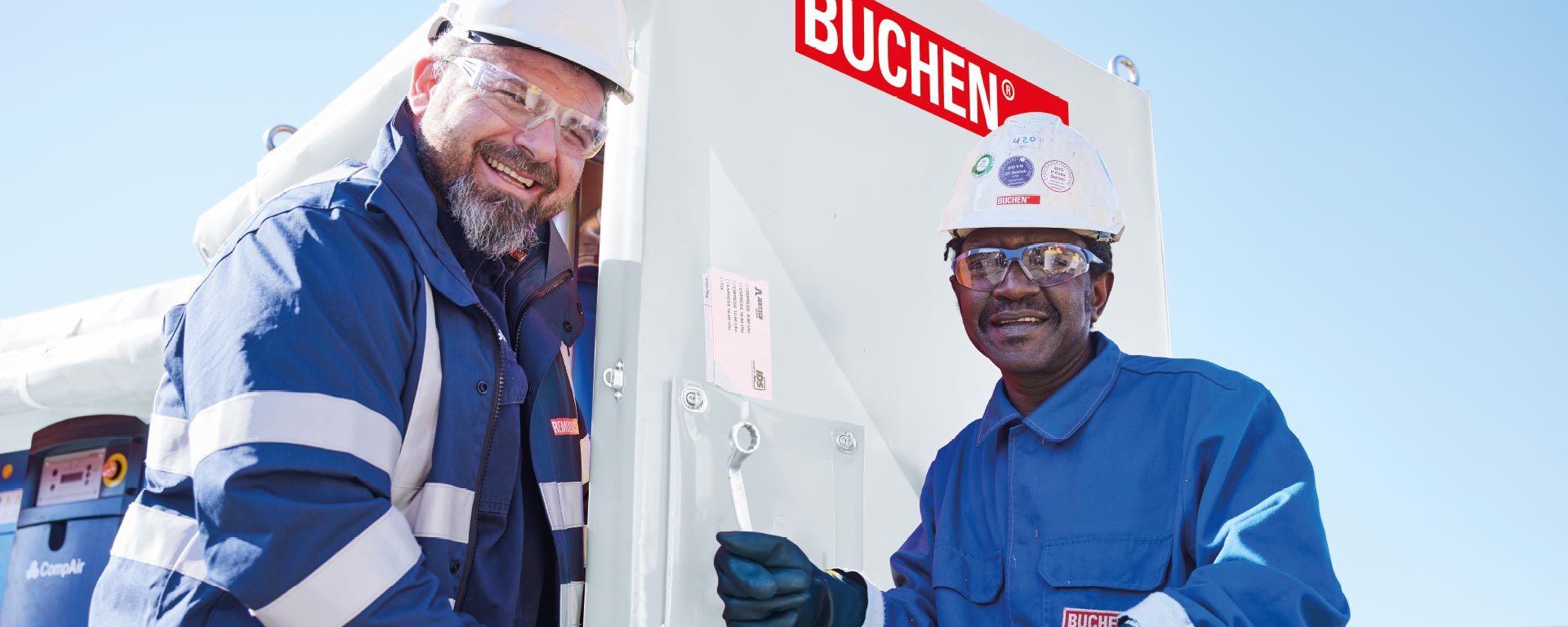 Two employees smile into the camera while they screw down a tube